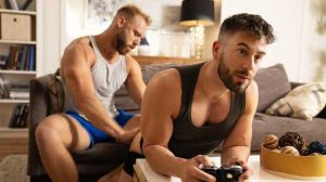 Blond hunk Brogan gets home horny, but Liam's concentrating so hard on his game, he can't get the bearded bottom's attention... until he pulls down his shorts and fingers his hole.